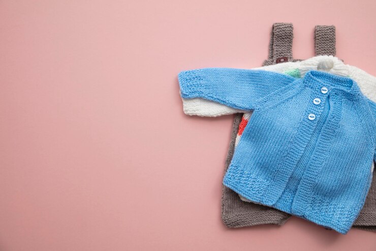 Foto lindo diseño de ropa de bebé de punto sobre un fondo rosa pastel