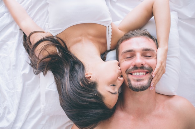 Lindo e atraente casal está deitado na cama cara a cara