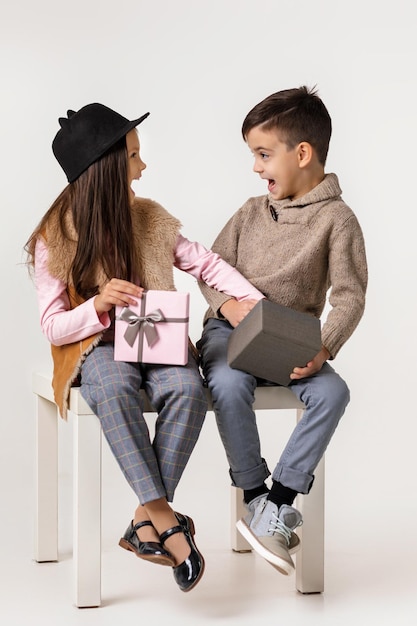 Lindo e estiloso casal criança menina e menino sentados juntos