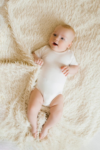 Lindo y encantador niño caucásico blanco con ojos azules acostado en la cama sonriendo a la cámara