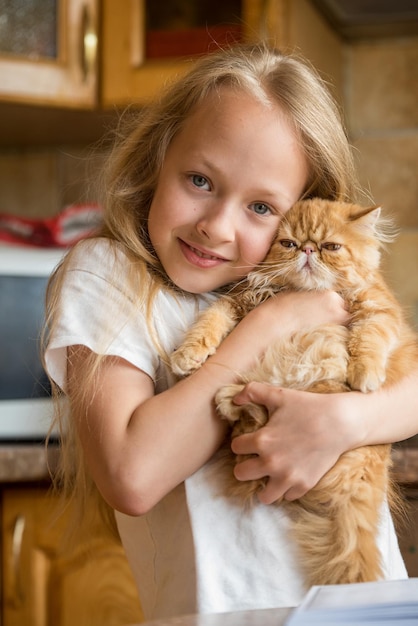 Lindo gatito doméstico persa en niñas mano gato y niño en casa