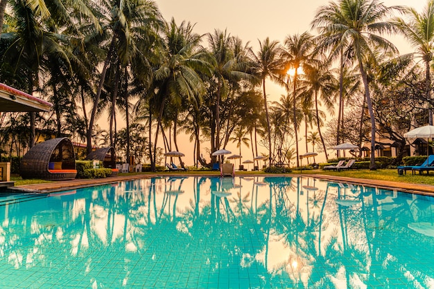 Lindo guarda-chuva e cadeira ao redor da piscina no hotel e resort