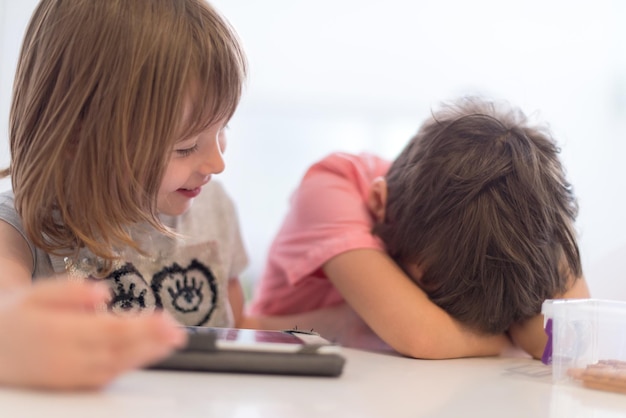 lindo hermanito y hermana divirtiéndose en casa los niños jugando en la computadora de la tableta