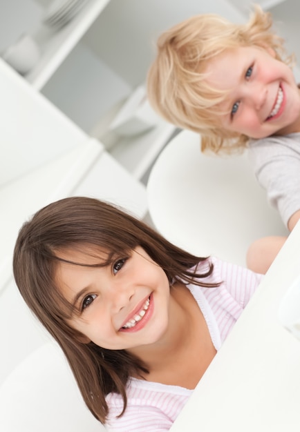 Foto lindo hermano y hermana sentada en una mesa en la cocina