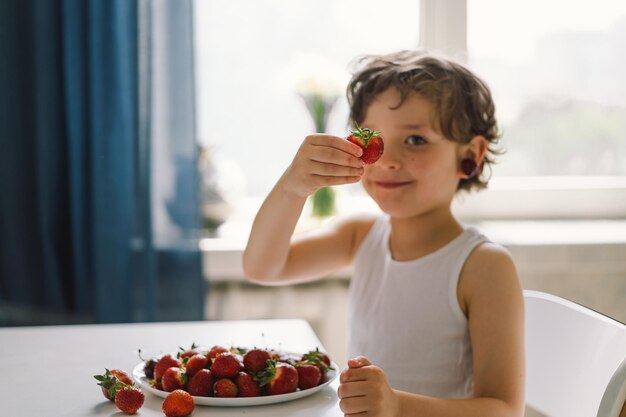 Lindo y hermoso niño comiendo cerezas frescas y fresas Alimentos saludables infancia y desarrollo