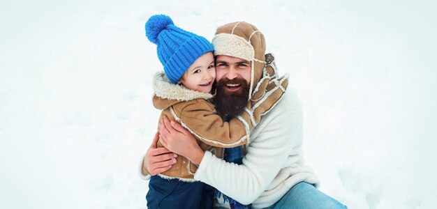 Lindo hijo abraza a su padre en vacaciones de invierno papá y niño sonriendo y abrazando a padre e hijo haciendo nieve