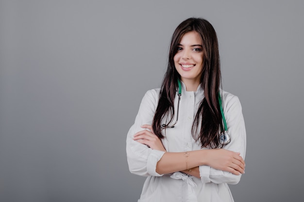 Lindo jovem médico sorridente em roupão médico isolado sobre cinza