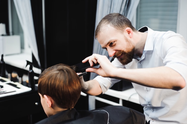 Lindo joven cortarse el pelo en la barbería.