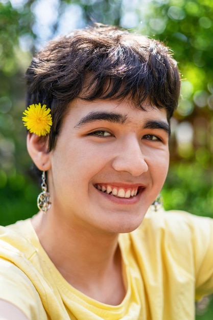 Lindo joven con una flor en el pelo y aretes en las orejas