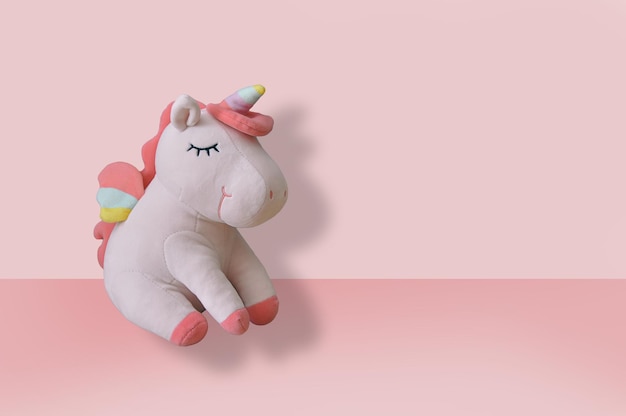 Lindo juguete de peluche de unicornio suave sobre fondo rosa Primer plano espacio vacío