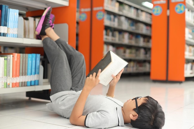 Lindo libro de lectura de niño pequeño en la biblioteca