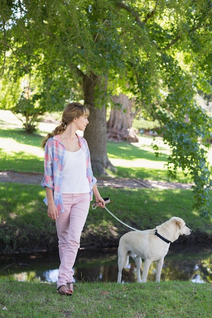 Lindo loira com seu cachorro labrador no parque