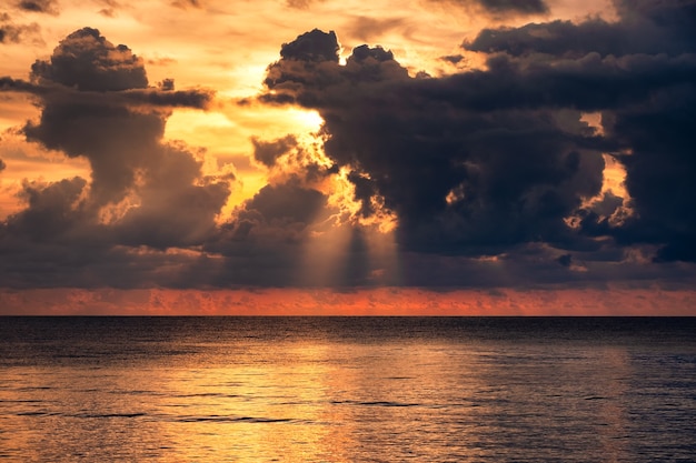 Lindo mar tropical com luz do sol através de nuvens dramáticas ao pôr do sol