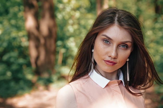 Lindo modelo feminino em pé de vestido rosa na floresta verde