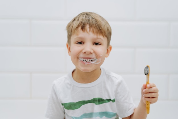 Lindo niño de 5 años cepillarse los dientes con un cepillo de dientes de bambú en el baño Imagen con enfoque selectivo
