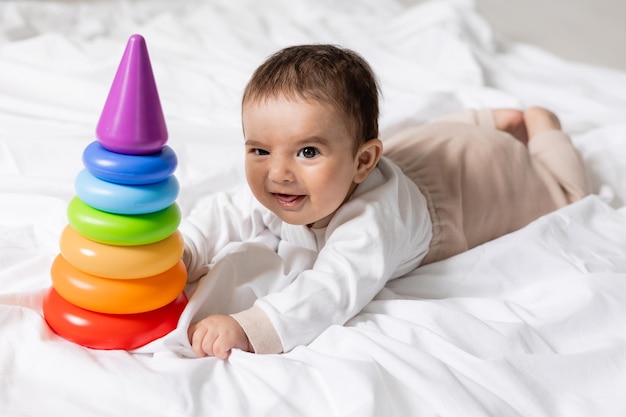 lindo niño acostado en una manta y jugando con una colorida tarjeta de juguete piramidal banner salud