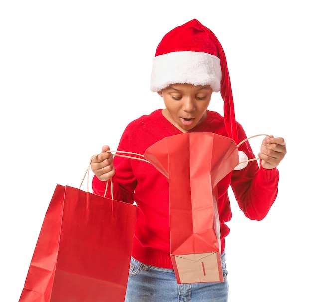 Lindo niño afroamericano con gorro de Papá Noel y con bolsas de la compra.