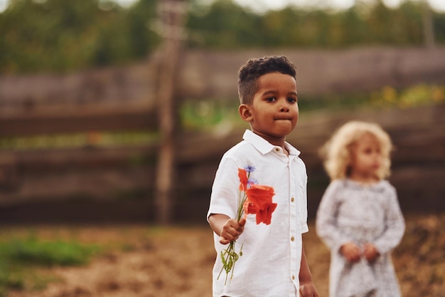 Lindo niño afroamericano con niña europea está en la granja