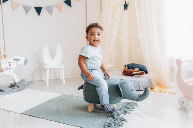 Un lindo niño afroamericano se sienta en una trona en forma de diseño de habitación de elefante para niños