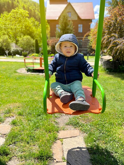 Un lindo niño de un año y medio monta en un columpio Patio trasero de la casa Entretenimiento infantil Enfoque selectivo