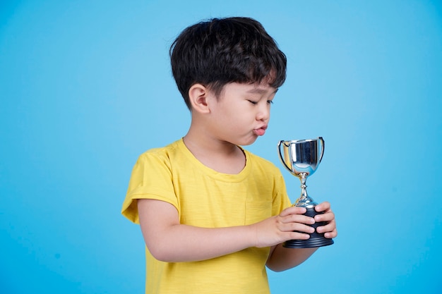 Lindo niño asiático sosteniendo un trofeo