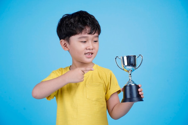 Lindo niño asiático sosteniendo un trofeo