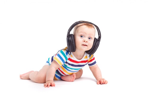 Lindo niño asombrado en camisa colorida con auriculares en la cabeza