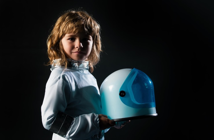 Foto lindo niño astronauta niño en traje espacial sosteniendo casco en fondo negro niños imaginando de
