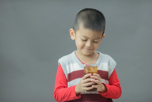 Lindo niño bebiendo agua de vidrioPequeño niño asiático bebiendo refresco