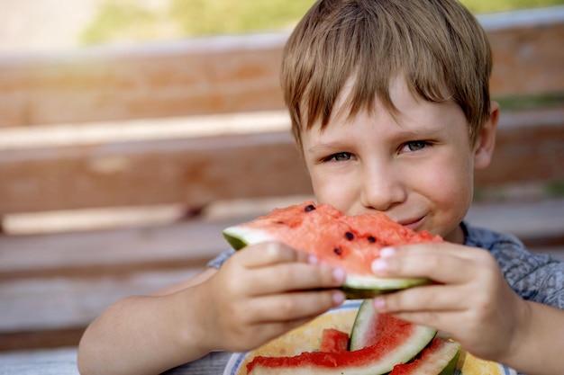 Lindo niño caucásico comiendo sandía en el campo