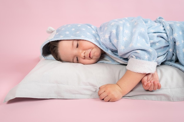 Lindo niño caucásico durmiendo en su almohada sobre fondo rosa Concepto de sueño infantil Foto de alta calidad