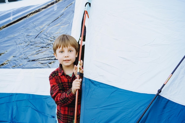 Lindo niño caucásico mirando desde la tienda turística Concepto de camping familiar