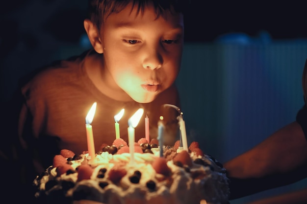 Lindo niño caucásico soplando velas pn pastel de cumpleaños