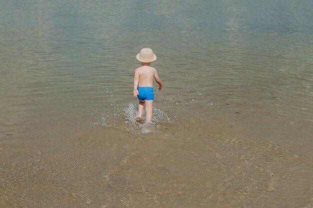 Lindo niño corriendo de las olas del mar en la playa