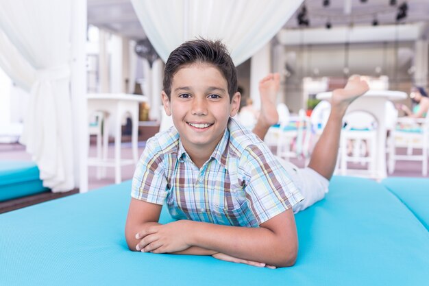 Lindo niño disfrutando en la cama turquesa