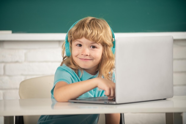 Lindo niño divertido usando computadora portátil niño estudiando a través de elearning en línea pequeño sistema divertido...