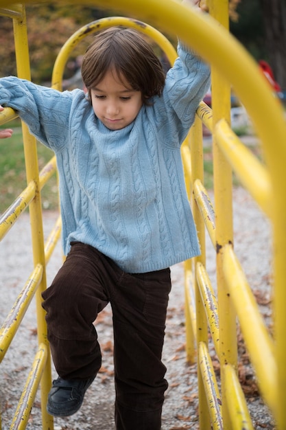 lindo niño divirtiéndose en el parque infantil el día de otoño cludy