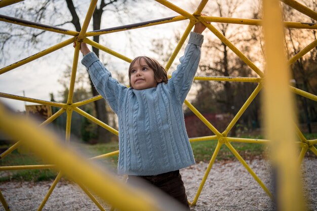 lindo niño divirtiéndose en el parque infantil el día de otoño cludy