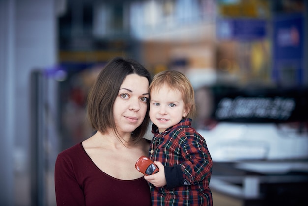 Lindo niño de dos años en manos de la madre durante la caminata en lugar público