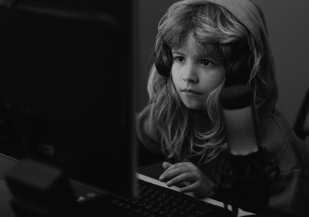 Lindo niño en edad preescolar viendo una lección en video de una computadora portátil, un niño pequeño blogger, un niño pequeño usa un