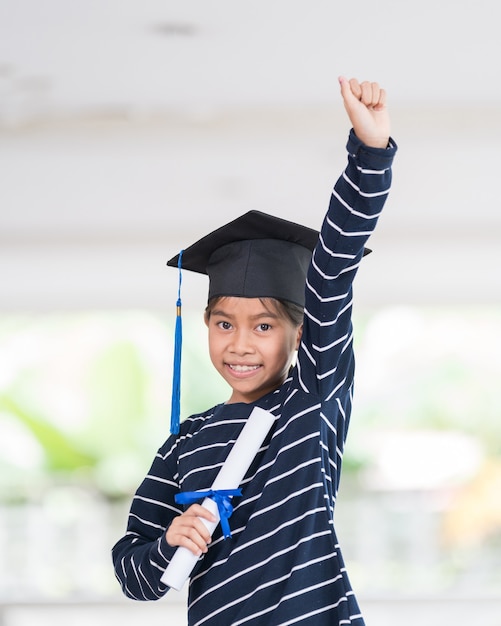 Foto lindo niño de escuela asiática feliz graduado con sombrero de graduación y un diploma aislado sobre fondo blanco.