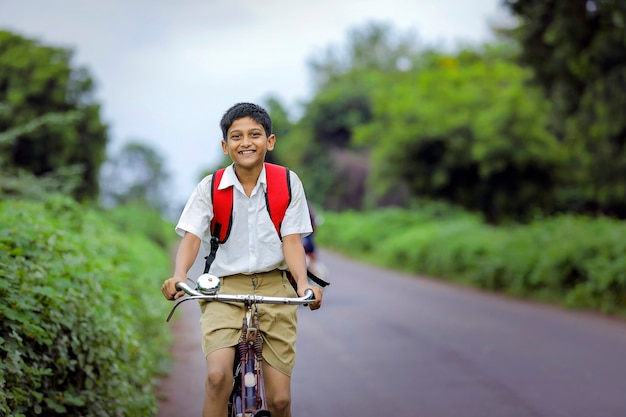 Lindo niño de la escuela india que va a la escuela en ciclo