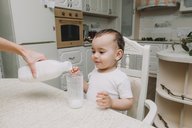 Lindo niño está bebiendo leche en la mesa de la cocina botella de leche mocap