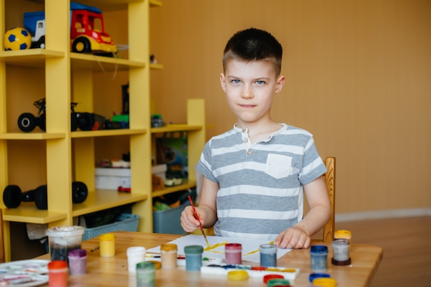 Un lindo niño está jugando y pintando en su habitación. Recreación y entretenimiento. Quédate en casa.