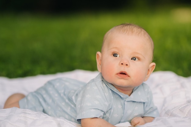 Lindo niño feliz acostado sobre una manta en el césped al aire libre en verano