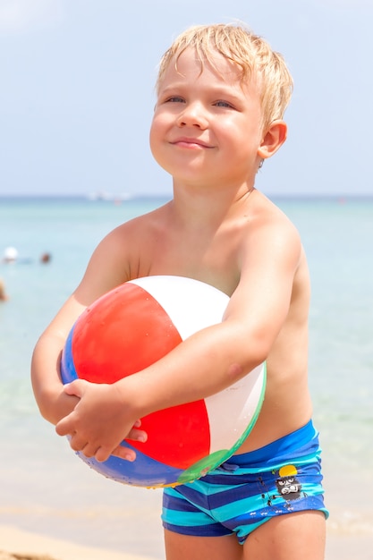 Lindo niño feliz divertido jugando en las olas del agua en el mar océano en un día soleado