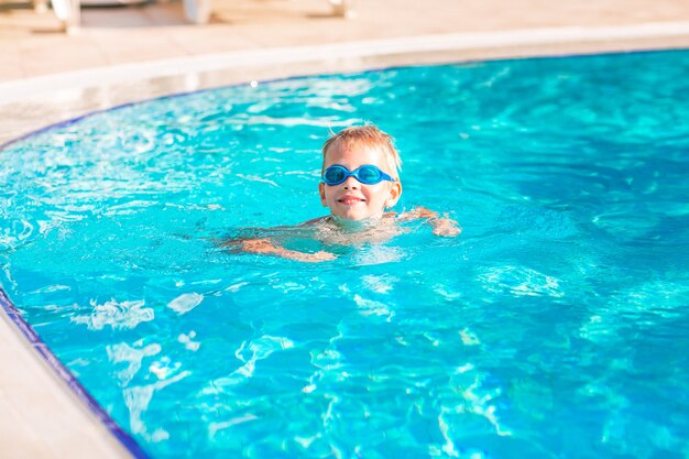 Lindo niño feliz en gafas de natación y snorkel en la piscina. Natación para el concepto de niños