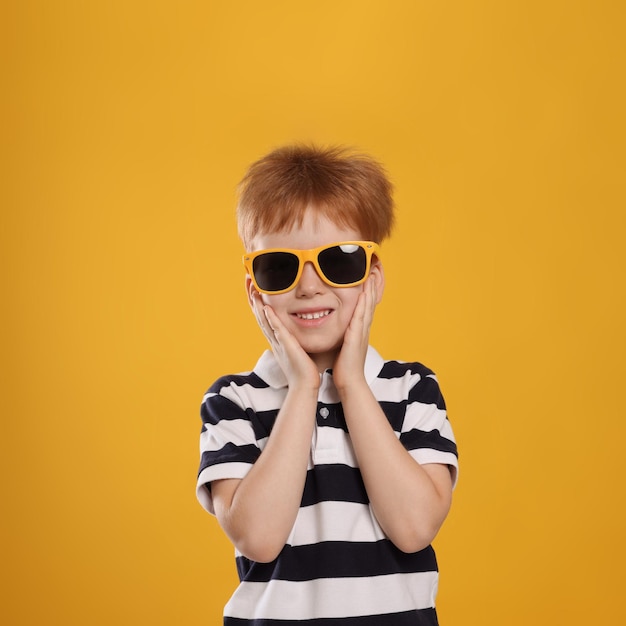 Lindo niño con gafas de sol sobre fondo amarillo