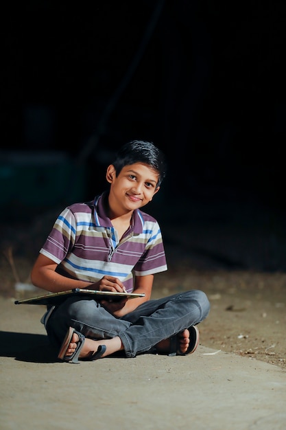 lindo niño indio escribiendo en pizarra