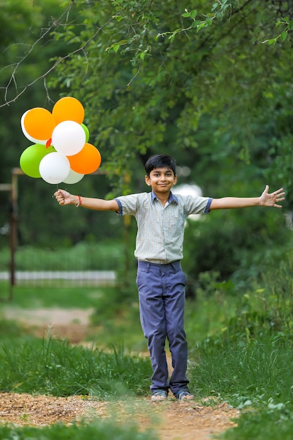 Lindo niño indio con globos de tres colores y celebrando el día de la independencia o la República de la India